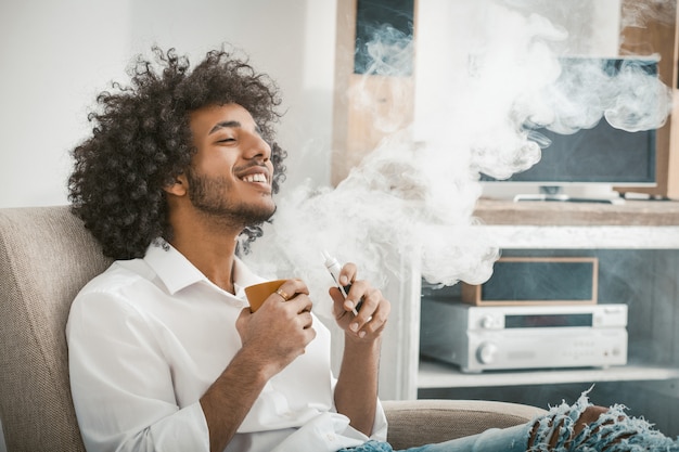 De knappe mens geniet van ontspannend holdingskop van drank in zijn handen