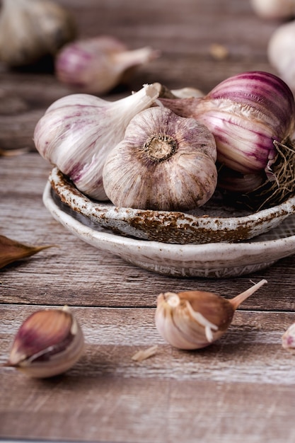 De knoflookbollen, in plakjes, op keramische plaat op een houten tafel, verticaal formaat