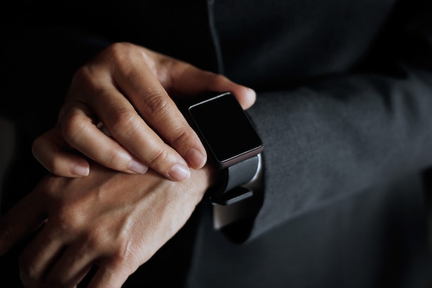 De knoop van de zakenmanpers vindt baan op slim horloge in hand, donkere achtergrond