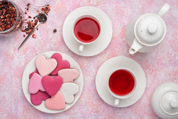 De koekjes van de hartvorm met suikerglazuur met bessenthee. concept: valentijnsdag theekransje, feestelijke tafel instelling in roze.