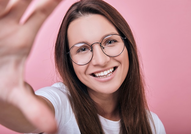 De koele vrouw in glazen in T-shirt en glazen neemt een selfie