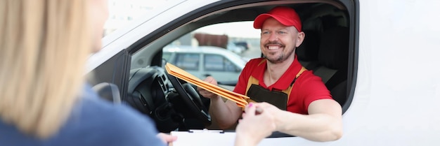 De koerier zit in de auto en geeft het pakketje aan de vrouw