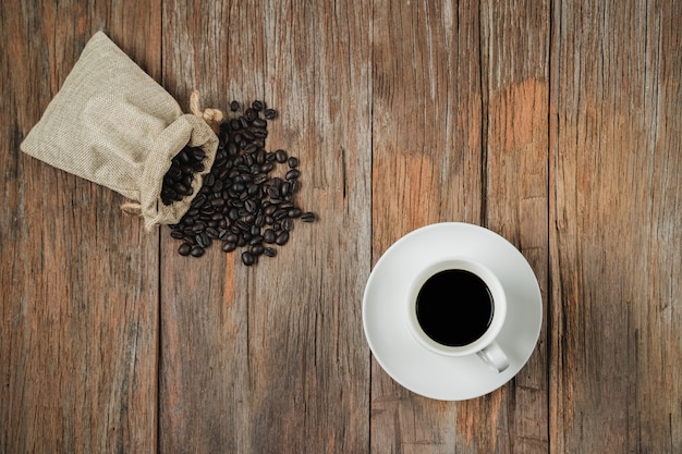 De koffiekop en de koffiebonen doen op rustieke houten textuurlijst in hoogste mening met copyspace in zakken