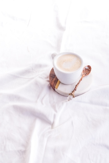 De koffiekop in de ochtend op de witte bed vlakke achtergrond, legt