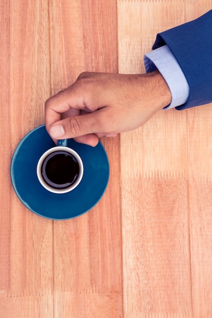 De koffiekop van de zakenmanholding bij bureau in creatief bureau