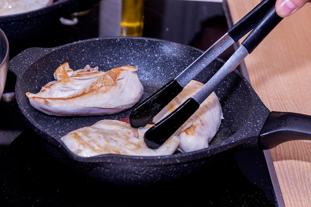 Foto de kok bakt kippenvleesfilet in een koekenpan.