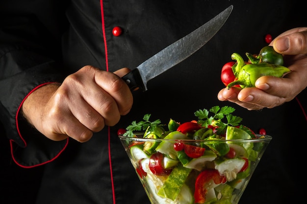 De kok bereidt vegetarische gerechten in een schaal voor Heerlijke salade van verse groenten door de handen van een kok in de keuken Menu idee voor een hotel of restaurant