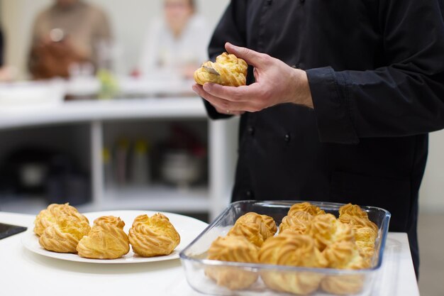 De kok maakt eclairs Snijd de eclairs en leg de room erop