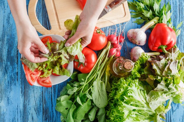 De kok scheurt sla terwijl het maken van verse de zomersalade, close-upspruit