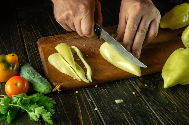 De kok snijdt gele paprika's op een snijplank om een vitaminesalade voor te bereiden Heerlijk vegetarisch eten voor de lunch Aziatische keuken