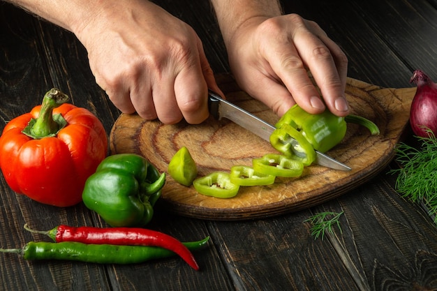 De kok snijdt groene paprika's op een snijplank om een vitaminesalade te bereiden Heerlijk boerenvoedsel
