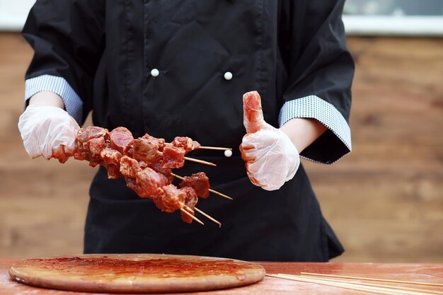 De kok snijdt vlees voor het koken van de barbecue op tafel