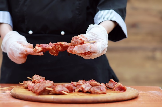 De kok snijdt vlees voor het koken van de barbecue op tafel