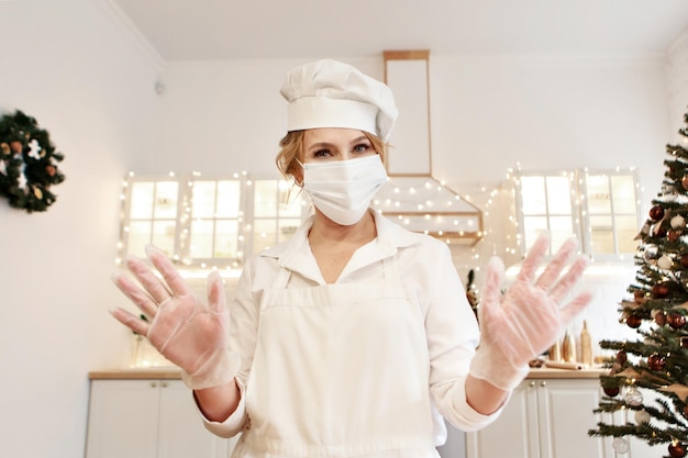 De kok staat in beschermende kleding in de keuken. de gastvrouw maakt een kerstdiner klaar. nieuwjaarsvakantiede kok bereidt gebak