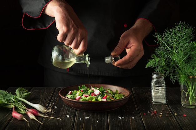 De kok voegt plantaardige olie toe aan een bord groentesalade Dieetontbijt of diner