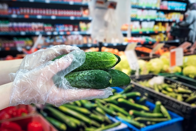 De koper in handschoenen kiest groenten tijdens een pandemie vanwege een nieuw gevaarlijk virus, coronavirus