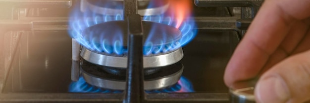 De kosten van gas voor huishoudelijke behoeften De hand draait de gasbrander in de keuken los Het gebruik van gas als huisverwarming in de winter tijdens het koude seizoen