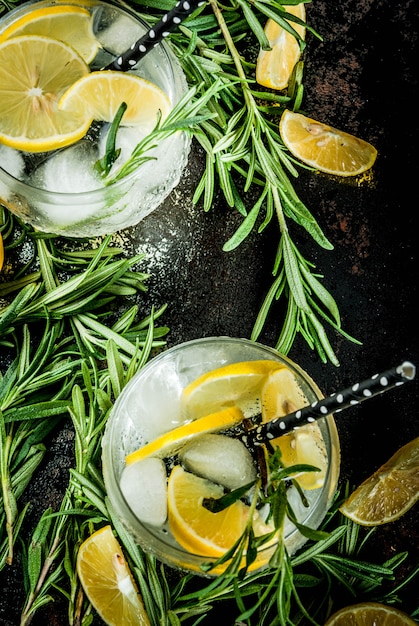 De koude limonade of alcoholwodkacocktail met citroen en rozemarijn, op een zwarte roestige oppervlakte, kopieert ruimte hoogste mening