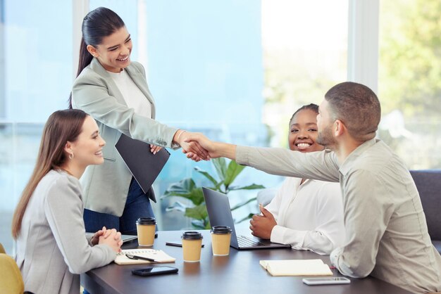 De kracht van het team zit in elk individueel lid shot van twee collega's die elkaar de hand schudden tijdens een meeting met collega's in een boardroom