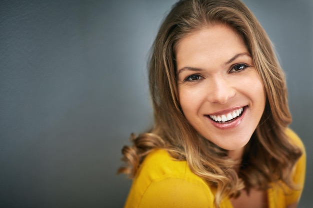 De kracht van vertrouwen is grenzeloos Shot van een jonge vrouw die poseert tegen een grijze muur