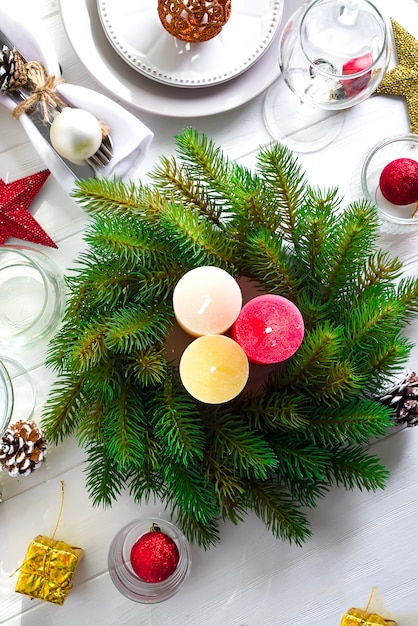 De kroon van Kerstmis met kleurrijke grote kaarsen op een tafel met een kerst tabel instelling