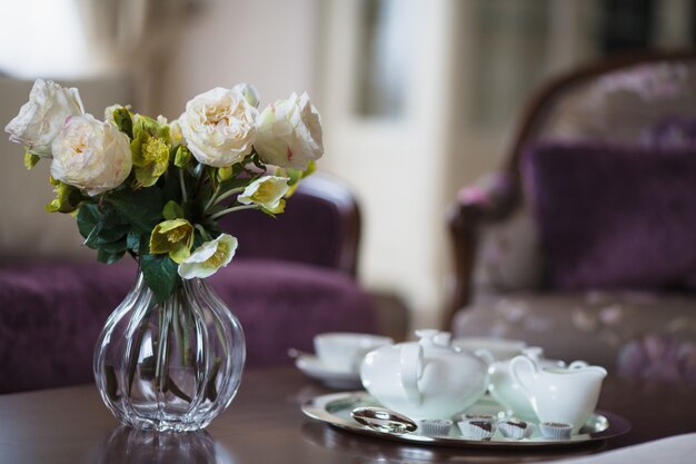 De kruik van het glas met bloemen en koffiekoppen