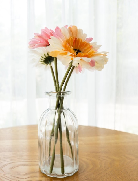 De kunstbloem in de helderglazen vaas op de houten tafel