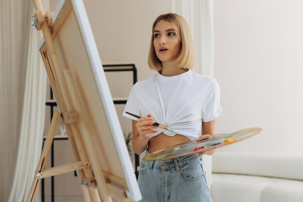 De kunstenaar schildert in de studio Aantrekkelijk meisje met een wit T-shirt