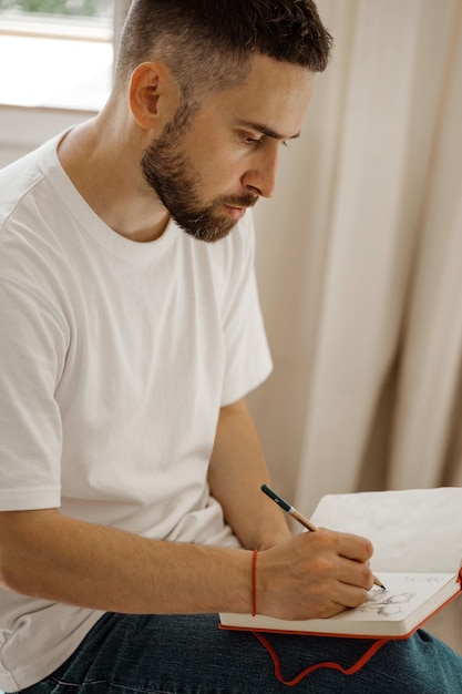 Foto de kunstenaar zit op een stoel en maakt een schets portret van een man die een potloodschets maakt creatieve workshop lifestyle het proces van het maken van een kunstwerk de zoektocht naar inspiratie