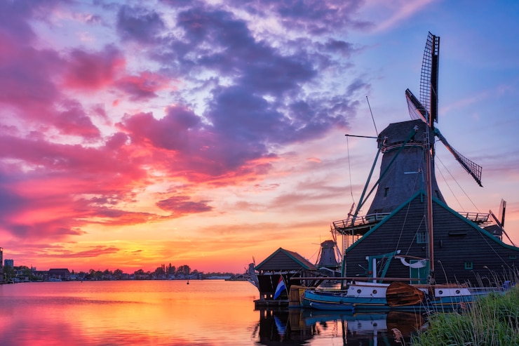 Foto de landelijke scène van nederland - windmolens bij beroemde toeristenplaats zaanse schans in holland op zonsondergang met dramatische hemel. zaandam, nederland