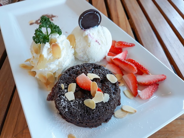 De lavacake van de chocolade met roomijs en vers fruit op witte plaat.