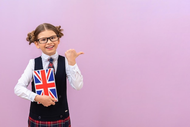 De leerling wijst naar uw advertentieruimte. studeren op school en het vertalen van vreemde talen. middelbare school onderwijs. een schoolmeisje met een leerboek op een geïsoleerde achtergrond.