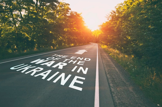 Foto de lege weg in het bos en de tekst op het asfalt het einde van de oorlog in oekraïne