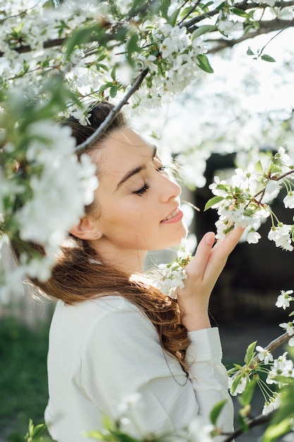 De lente komt eraan natuurlijke schoonheid mooie jonge vrouw onder witte bloesems in de lentetuin jong