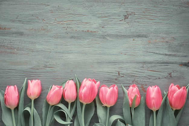 De lentemuur met roze tulpen op donker geweven hout, exemplaar-ruimte