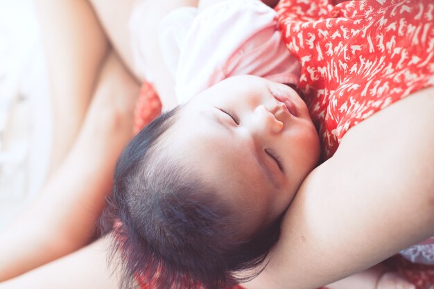 De leuke Aziatische pasgeboren slaap van het babymeisje op de schouder van de moeder