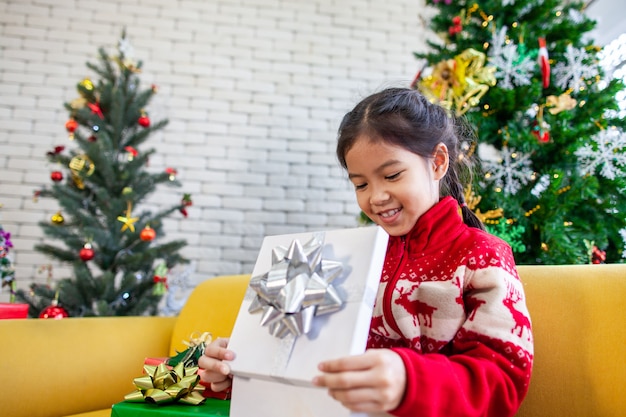 De leuke Aziatische verrassing van het kindmeisje met gift en het houden van mooie gift bij Kerstmisviering in hand