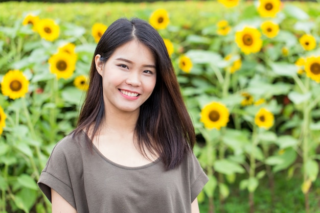 De leuke glimlach van de portret Aziatische Thaise tiener met zonnebloem met exemplaarruimte.