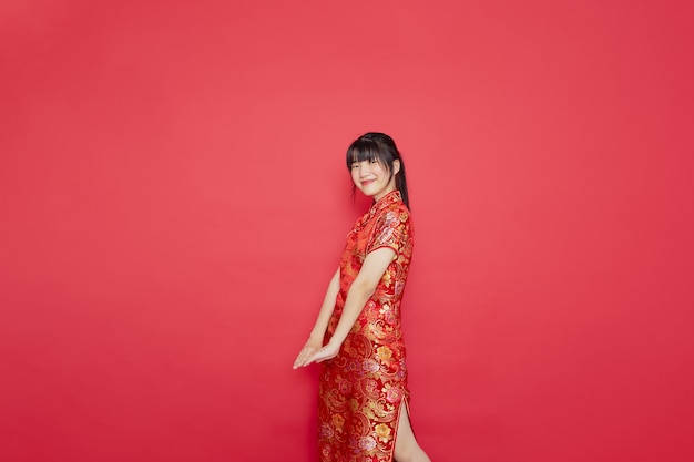 De leuke jonge Aziatische cheongsam van de vrouwenkleding met actie voor Chinees nieuwjaarconcept