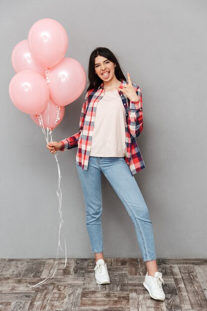 De leuke mooie jonge ballons van de dameholding maken rotsgebaar.