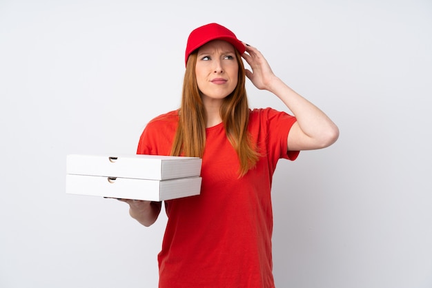 De leveringsvrouw die van de pizza een pizza over geïsoleerde roze muur houdt die twijfels heeft en met verwarring gezichtsuitdrukking