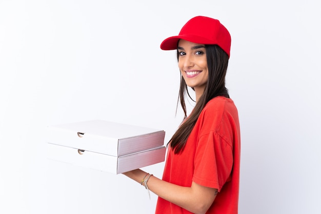 De leveringsvrouw die van de pizza een pizza over geïsoleerde witte muur houdt die veel glimlacht