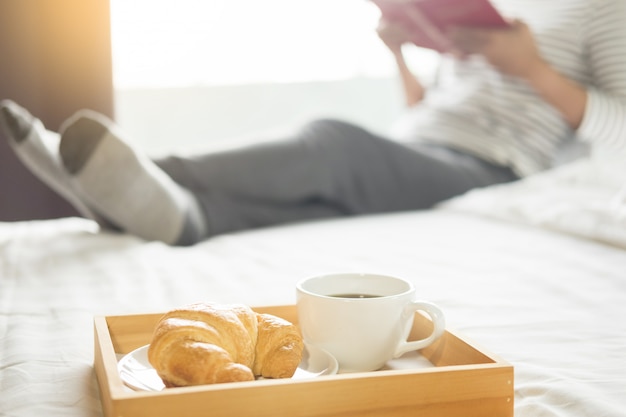 De lezingsboek of de krant van de vrouw en het drinken koffieontbijt op bed tijdens de ochtend.