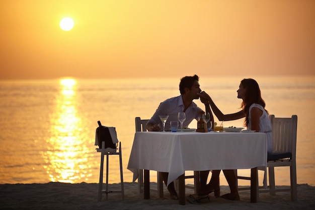 De liefde van zijn leven Een jonge man kust de hand van zijn vrouw tijdens een diner op het strand