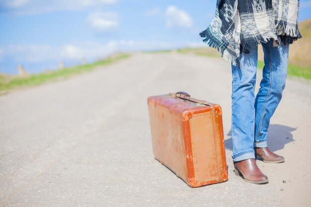 De lifterreiziger wacht op auto op weg met koffer