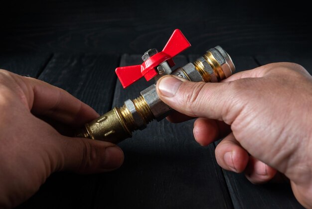 De loodgieter verbindt messing fittingen met kogelkraan Close-up van de hand van de meester tijdens het werken