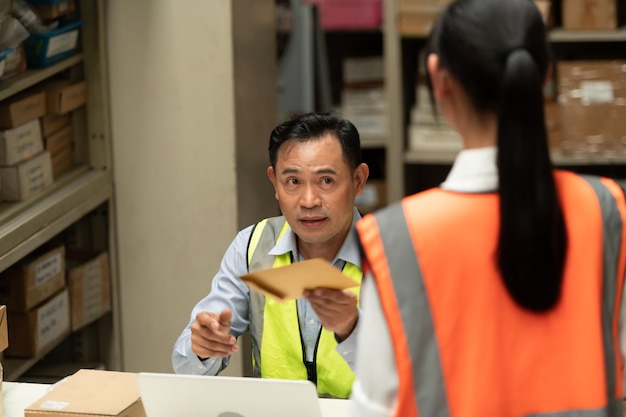 Foto de magazijnmanager gaf de vrouwelijke assistent een premie die hielp bij het werk en de planning van de voorbereiding van producten die aan de detailhandelaren werden verkocht totdat het zeer succesvol was.