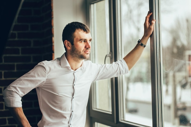 De man die bij het panoramische raam staat Hand op raam Blijf thuis tijdens quarantaine