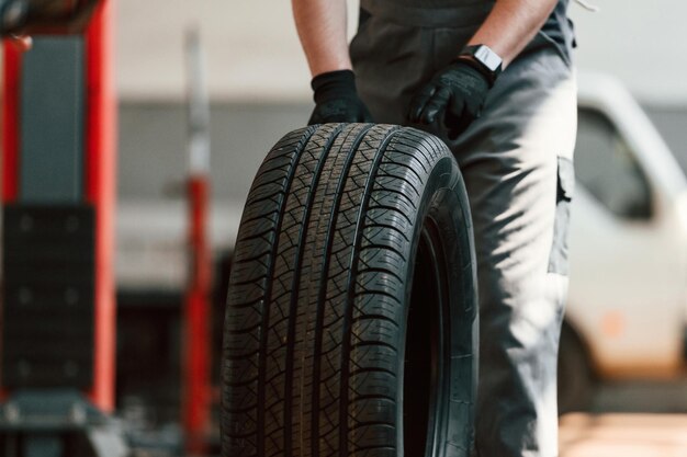 Foto de man die het wiel rolt werkt in de auto-reparatie salon.