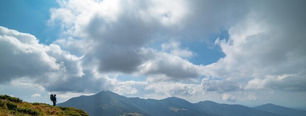 De man die op de berg staat op de wolkenachtergrond